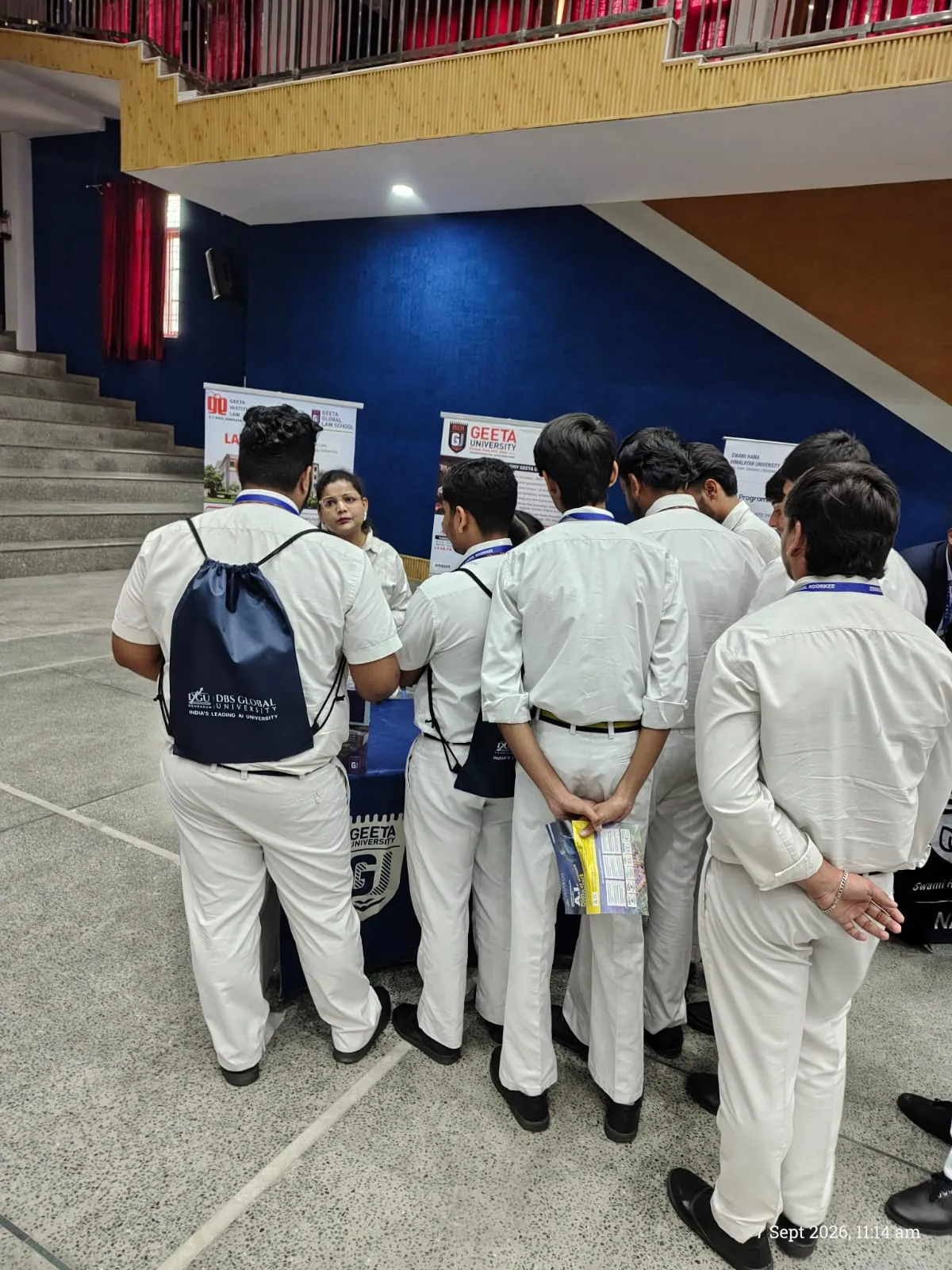University admissions representative with student cohort at information desk